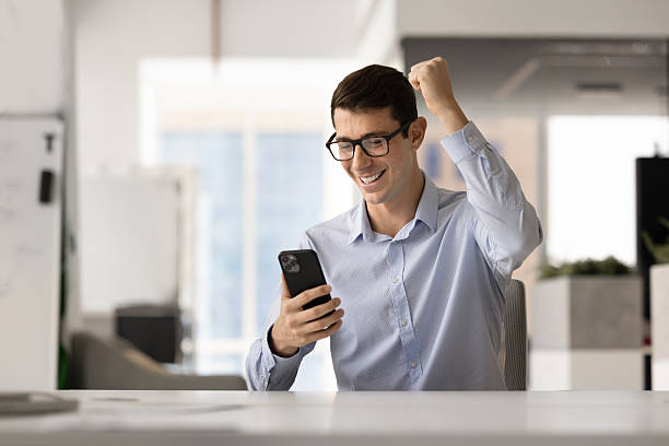 istock Excited young Latin businessman in glasses making triumph gesture 2244670272