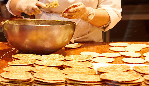 Baker's hands skillfully preparing Belgian waffles in a bakery display case, showcasing a variety of delicious treats with warm textures and inviting ambiance