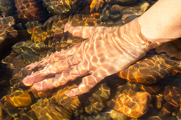 Hand touching the water of a clean and crystal clear river