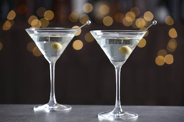 istock Martini cocktail with olives in glasses on grey table against blurred background, closeup. Bokeh effect 2244676029