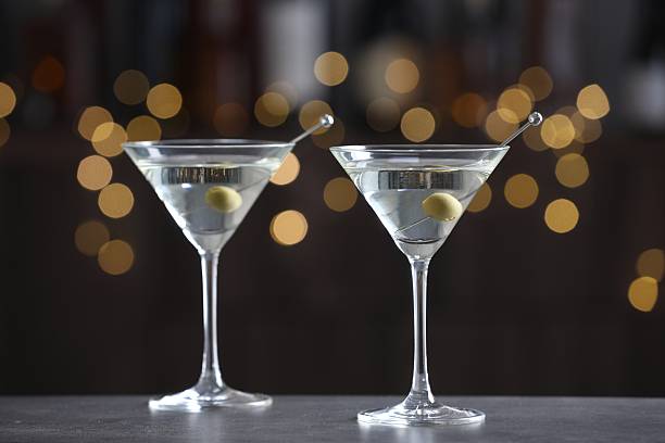 istock Martini cocktail with olives in glasses on grey table against blurred background. Bokeh effect 2244676071