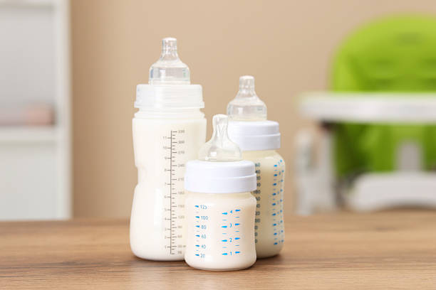 Feeding bottles with milk on wooden table indoors