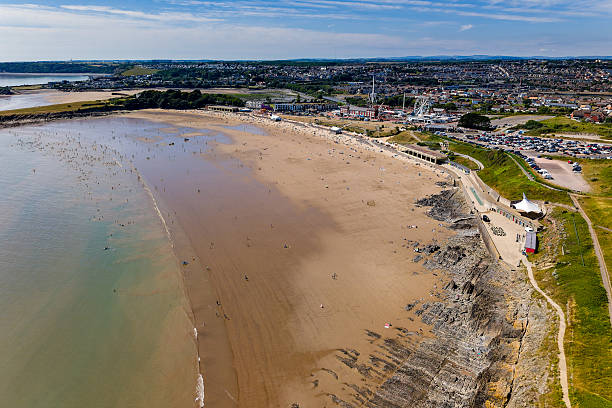 People enjoying a sunny summer day on the sandy beach of Barry Island resort