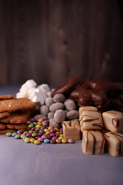 istock assorted sweets display featuring colorful candies, chocolate-coated treats, marshmallows, wafers, and fudge in a rustic indoor setting with soft ambient lighting, indulgent, contrast, color 2244682708