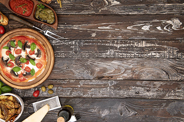 Homemade Italian pizza with mushrooms, basil and tomatoes on rustic wooden table. Copy space on the right for text, menu or recipe design.