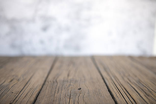 Old wooden surface with visible texture and cracks, blurred wall in background. Perfect neutral background for food, product or design mockup.