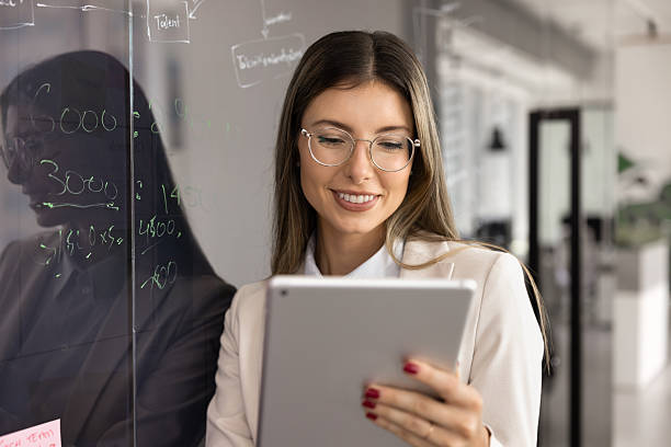 istock Positive business trainer woman in glasses using digital tablet computer 2244686369