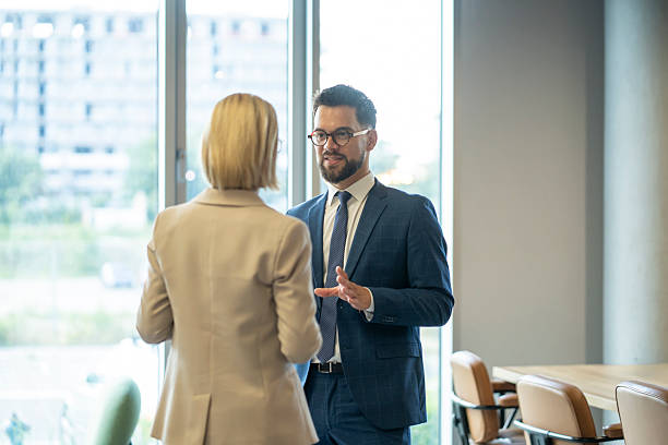 istock Two business professionals standing and discussing work in a bright, modern office. 2244690295