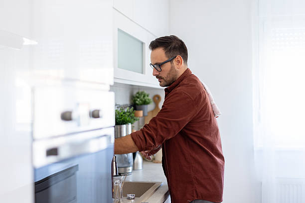 istock Man in Kitchen Washing Dishes with a Relaxed Expression 2244694243