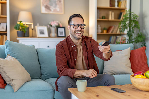 istock Smiling Man Enjoying TV Time with Remote in Bright Room 2244694259