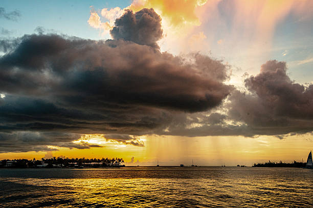 sunsets in key west Florida with beautiful clouds and rain from a pier with sailboats and jet skis