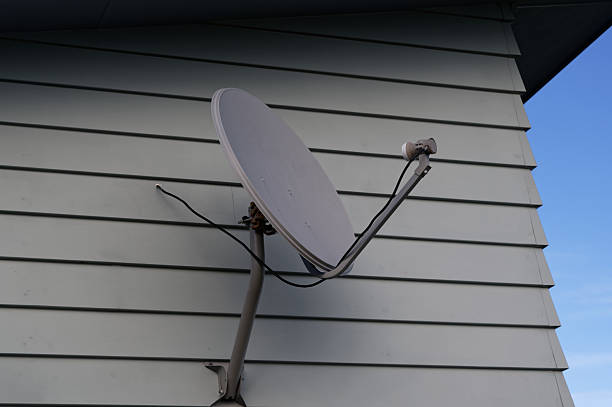 Television antenna mount. Yellow wood house facade with mounted satellite.