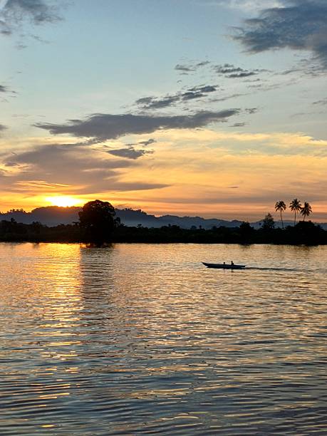 istock Golden Sunset Reflected on Calm Water with a Lone Boat Passing By 2244701119