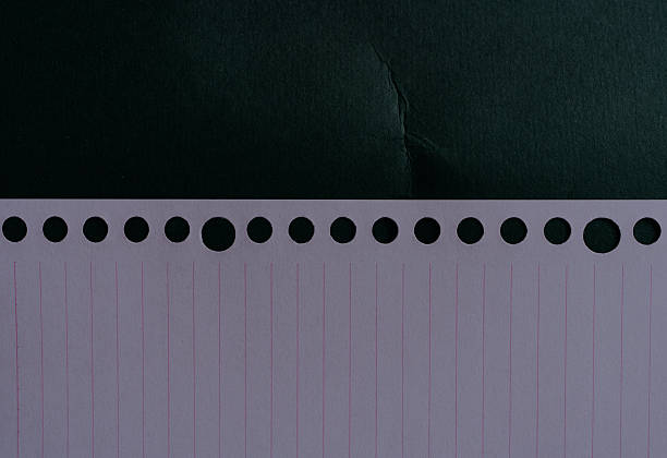 Cropped of blank lined notebook paper with hole on black background.