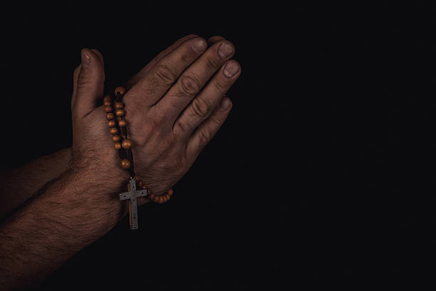istock Hands clasped in prayer with rosary in a dimly lit setting 2244706336