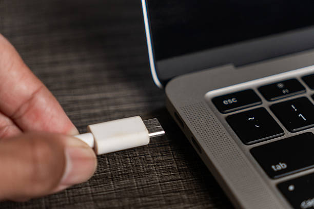 istock Hand Plugging White USB C Cable Connector into Grey Laptop Port 2244706396