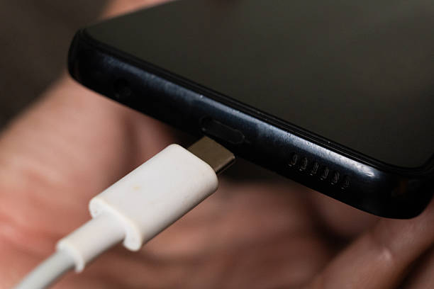 istock Macro Shot of White USB-C Plug Connected to a Black Smartphone for Charging 2244706490