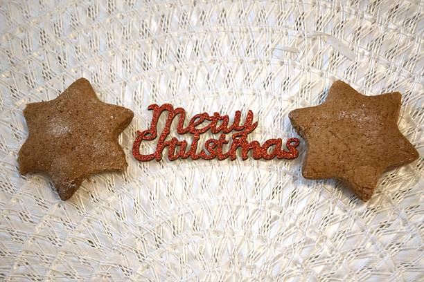 Red Merry Christmas lettering with two star-shaped gingerbread cookies and Copy Space. Festive holiday theme and sweet decoration.