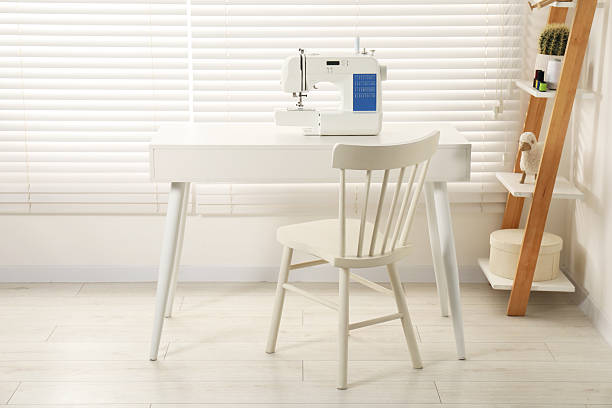 istock Sewing machine on white desk near chair indoors 2244716434