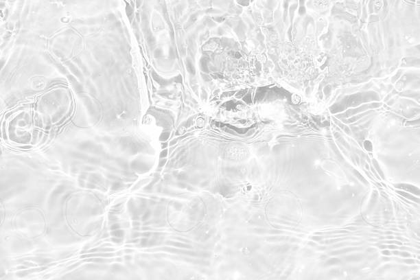 White water with ripples on the surface. Defocus blurred transparent white colored clear calm water surface texture with splashes and bubbles. Water waves with shining pattern texture background.