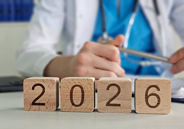 istock Doctor sits at a desk writing notes while wooden blocks the year 202 2244722974