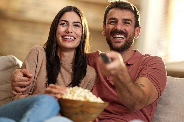 istock Happy couple eating popcorn while watching TV at home. 2244726315