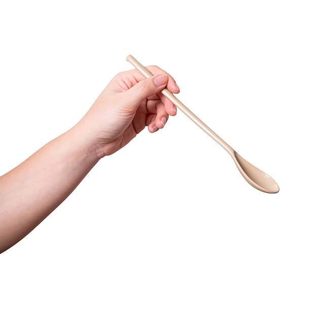 istock Female hand holding a brown plastic spoon isolated on white background. 2244727214