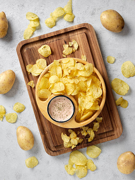 Potato chips and dip appetizers snacks on wooden board