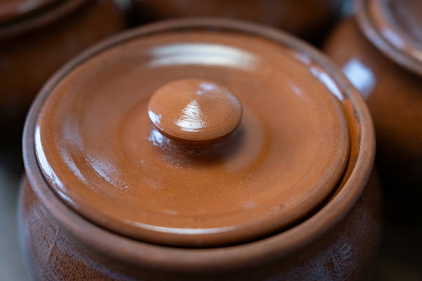 Close-up of traditional brown earthenware pots with lids. The rustic, glazed ceramic surface suggests slow-cooked, homemade meals and authentic culinary traditions.