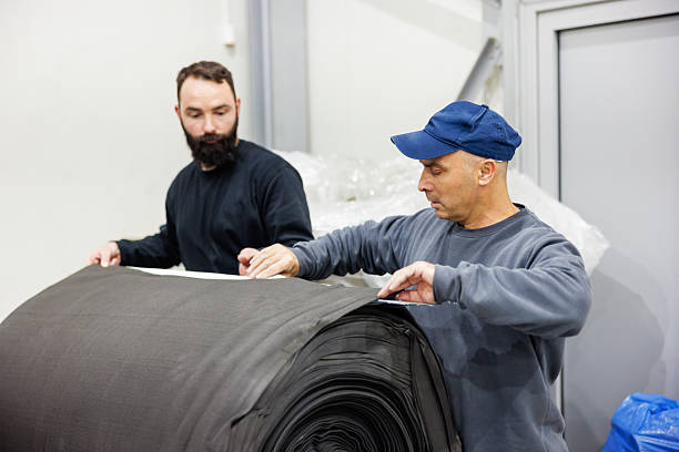 istock Workers handle roll of material in small scale industrial production line 2244736299