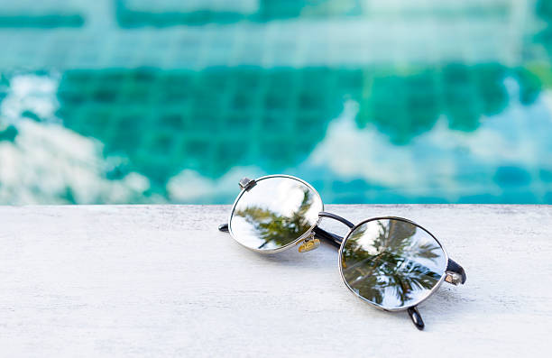 istock Sunglass with reflection of the palm tree with space on blurred swimming pool background 2244737721