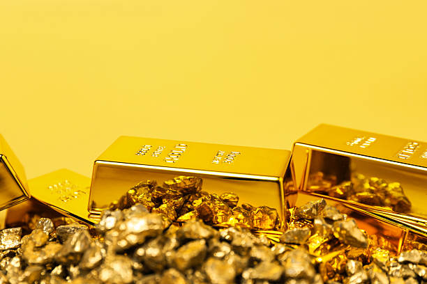 istock Gold nuggets and bars on yellow background, closeup 2244738582