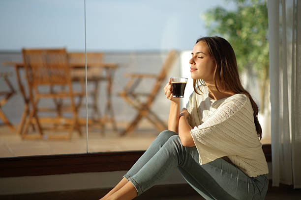 istock Woman smelling coffee beside a window 2244740856