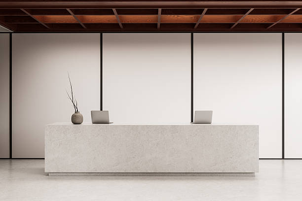 istock Minimalist reception counter with laptops and vase in modern office interior featuring wooden ceiling and neutral wall panels. 3D Rendering. 3D Rendering 2244741178