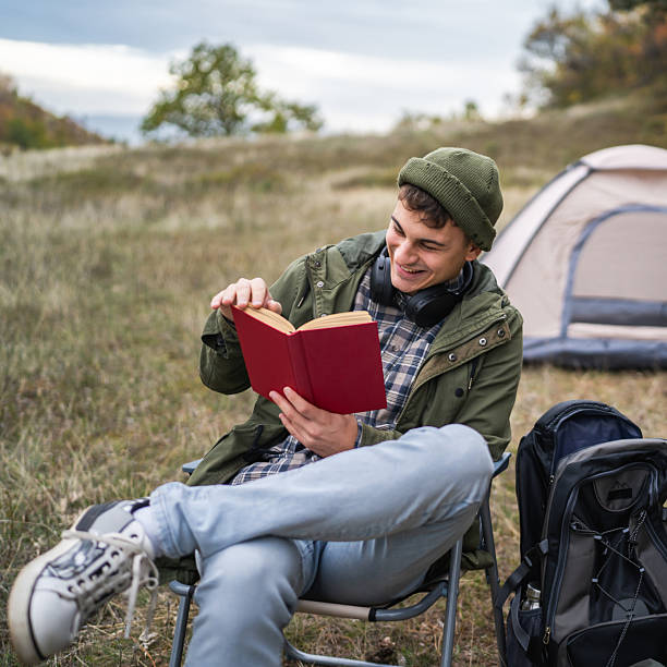 istock Young man enjoying reading book while camping in nature 2244742740