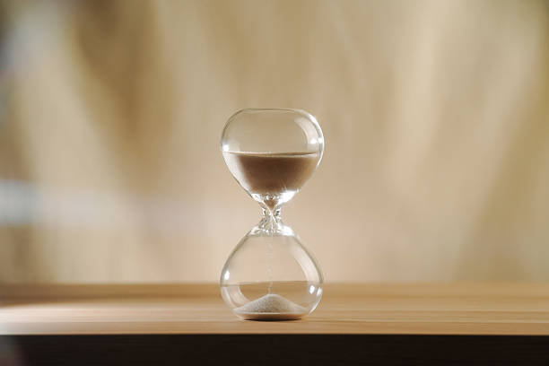 istock Minimalist Glass Half time Hourglass on Wooden Surface with Beige Background 2244745939