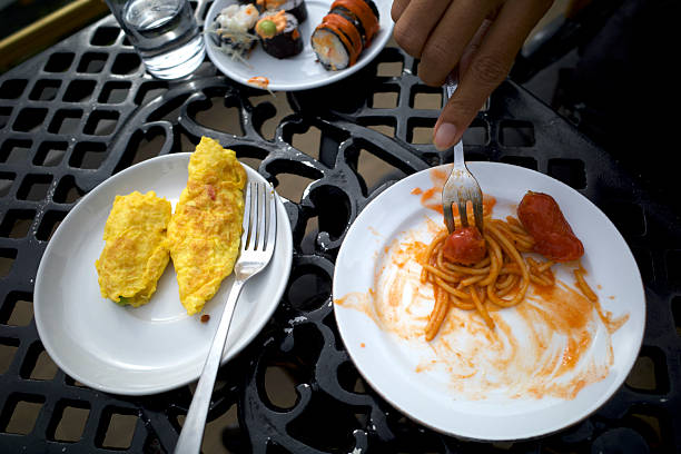 Cropped view of an unrecognizable couple sitting side by side and sharing a dish of pesto ravioli at a traditional trattoria in Little Italy, San Francisco, California.