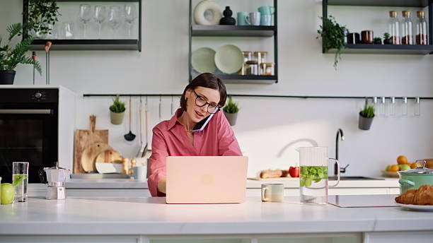 Online manager calling cellphone working laptop at kitchen home office closeup