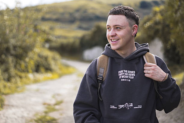 istock Smiling young hiker with backpack standing on mountain trail on a cloudy day 2244755473