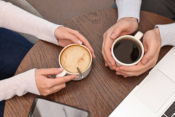 istock Colleagues having coffee break at wooden table in cafe, above view 2244756997