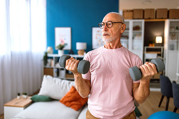 istock Senior man exercising at home, using dumbbells 2244759579