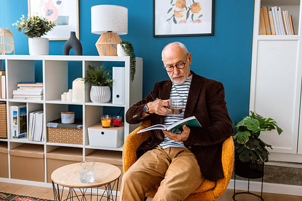 istock Senior man with eyeglasses sits in a comfortable armchair with a book in his hands 2244759727
