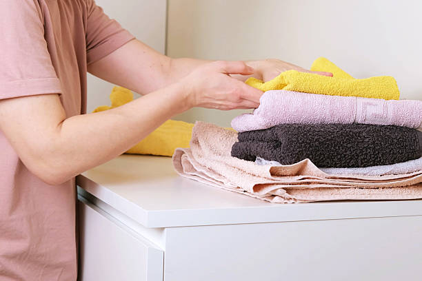 istock woman neatly stack dry, freshly laundered towels into a pile 2244760837