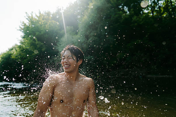 Photo of a young Asian man swimming in the river, on a hot summer day