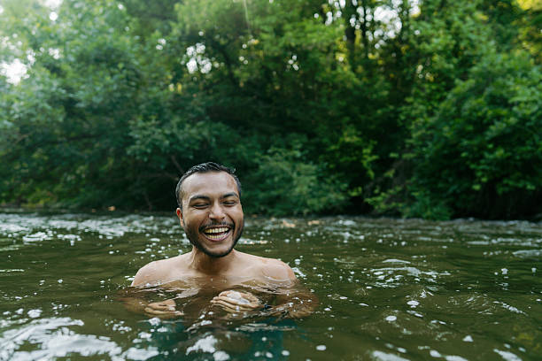 Photo of a young Asian man swimming in the river, on a hot summer day