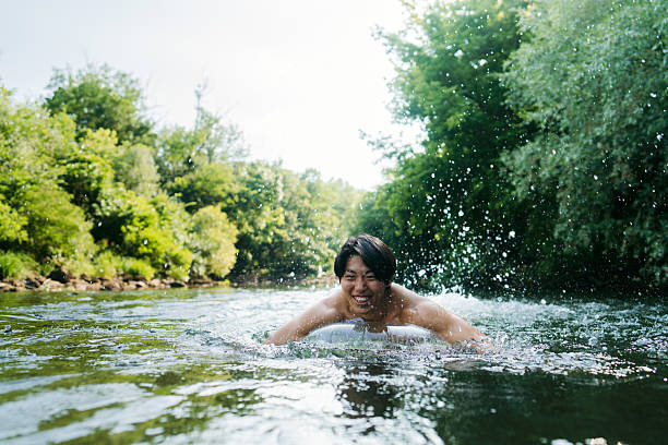Photo of a young Asian man swimming in the river, on a hot summer day