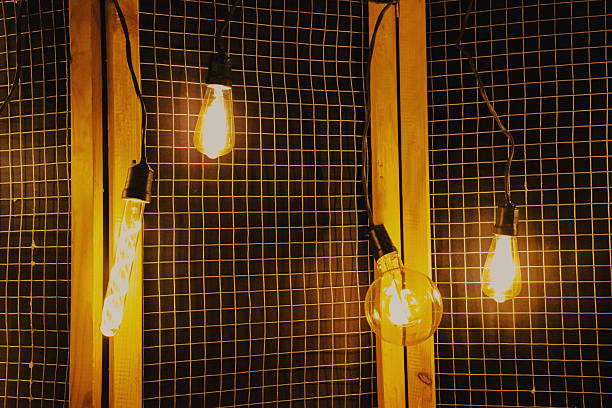 Vintage light bulbs hanging against a wooden grid backdrop, creating a warm ambiance, showcasing the beauty of illumination and design in a cozy setting