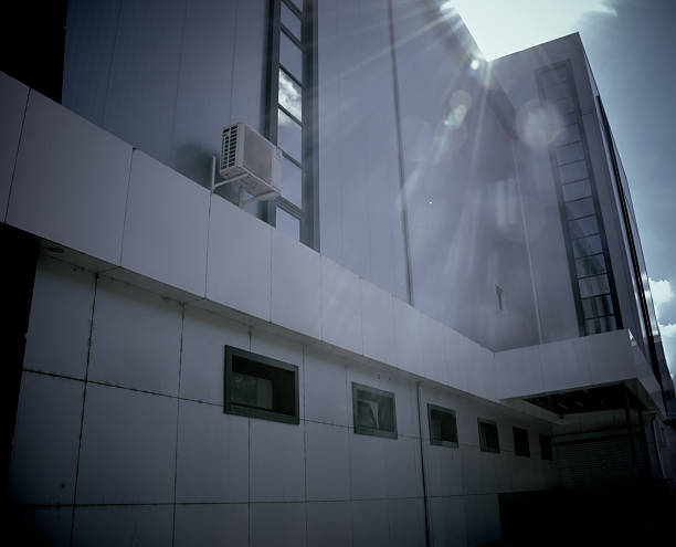 Exterior view of a modern industrial building featuring large windows, an air conditioning unit, and sleek surfaces, highlighting contemporary architectural style