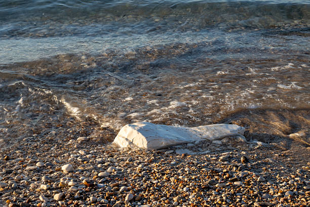Beach of Ionian sea, covered by various colors of pebbles. One big rock. Movement of the water during tide. Acharavi, Corfu (Korfu), Greece.