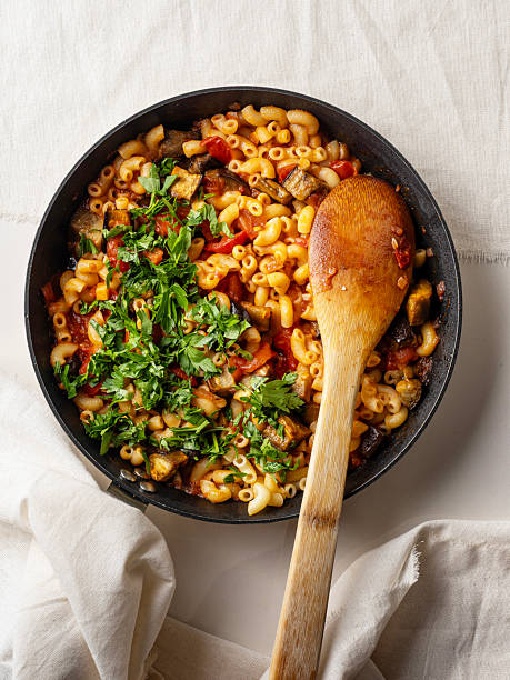 Pasta with eggplant and tomato sauce in pan. Macaroni. Pasta with eggplant and tomato sauce. Pasta, with grilled vegetables and herbs in frying pan, close-up.